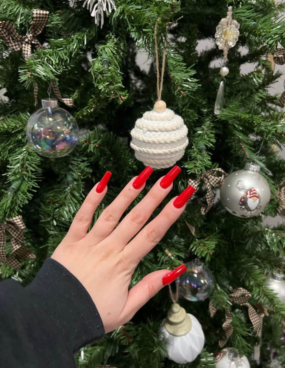 Long red almond nails against a Christmas tree